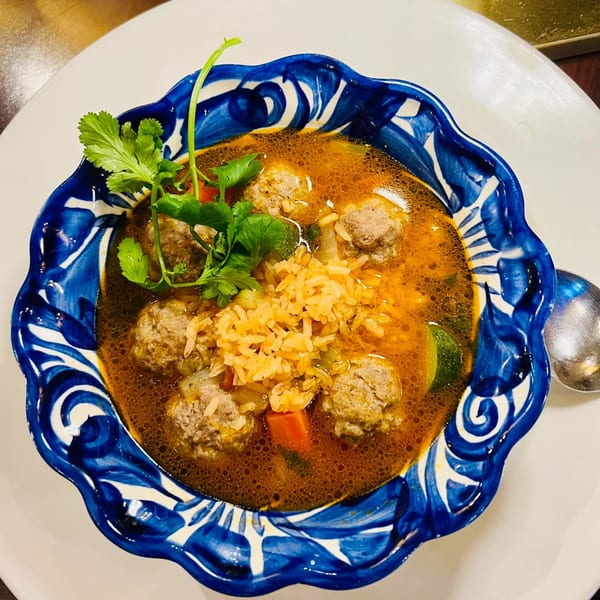 Favela's Mexican Grill's meatball soup with rice, vegetables, and cilantro in a blue and white bowl.